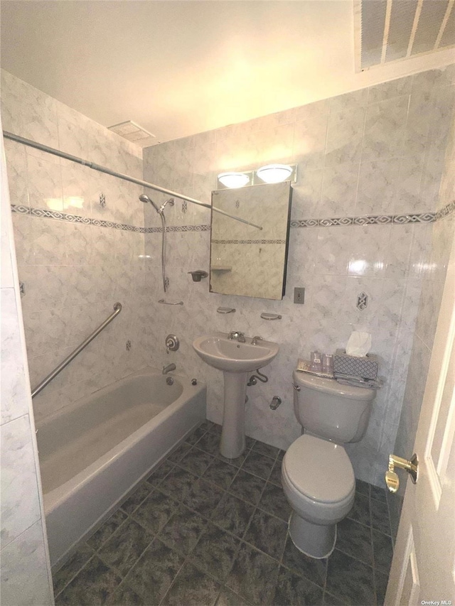 bathroom with tile patterned floors, toilet, tile walls, and bathing tub / shower combination