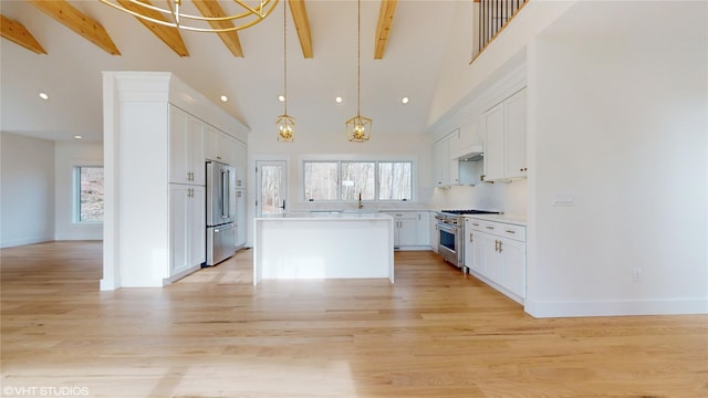 kitchen with premium appliances, light countertops, beam ceiling, and a healthy amount of sunlight