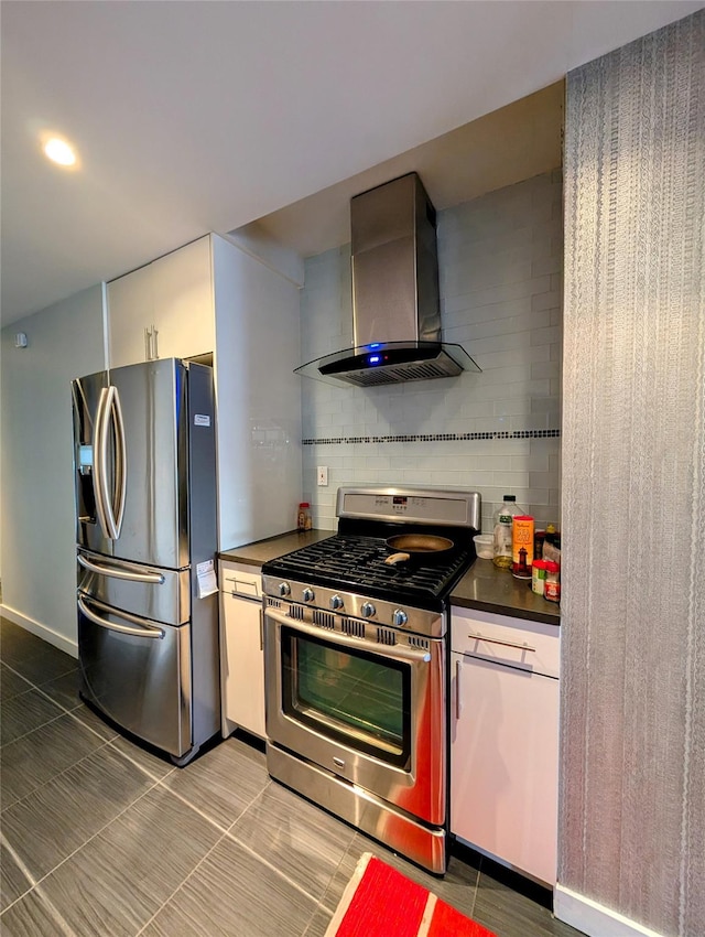 kitchen with appliances with stainless steel finishes, tile patterned floors, tasteful backsplash, and wall chimney range hood