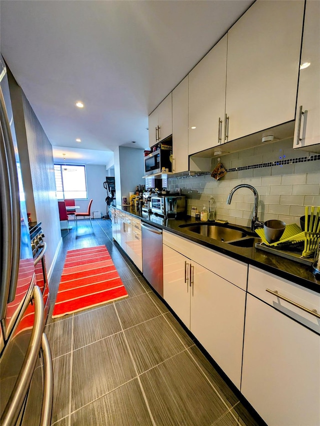 kitchen with tasteful backsplash, white cabinets, sink, and stainless steel appliances