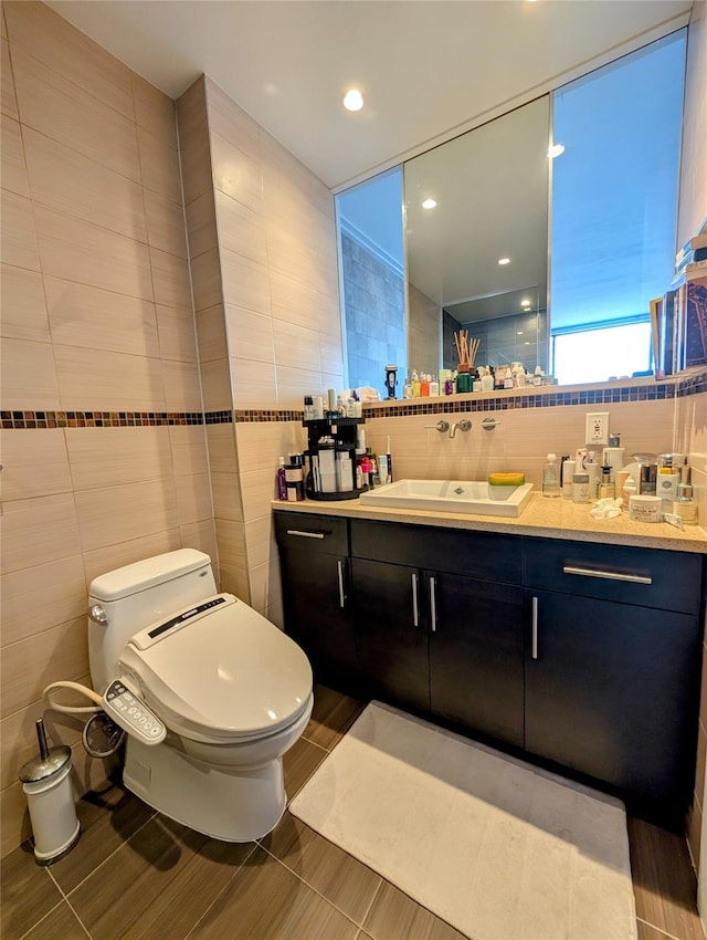 bathroom with toilet, vanity, and tile walls