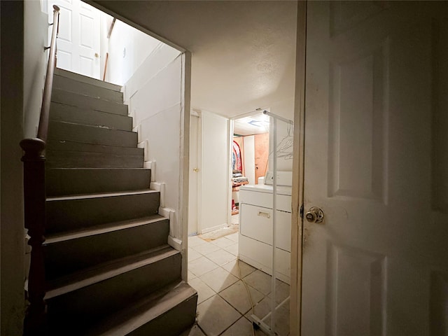 stairway with tile patterned flooring and separate washer and dryer