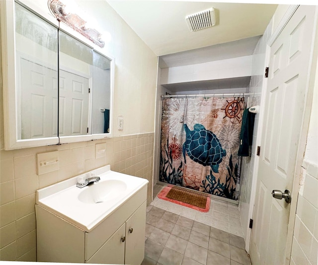 bathroom with tile patterned flooring, vanity, tile walls, and walk in shower