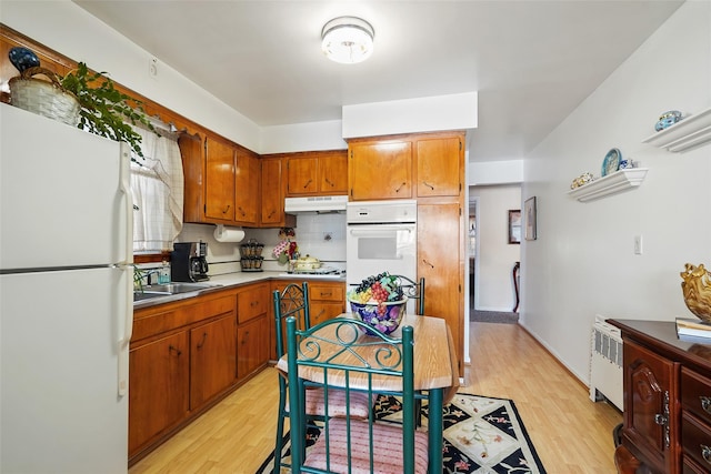 kitchen featuring white appliances, light hardwood / wood-style floors, tasteful backsplash, and sink