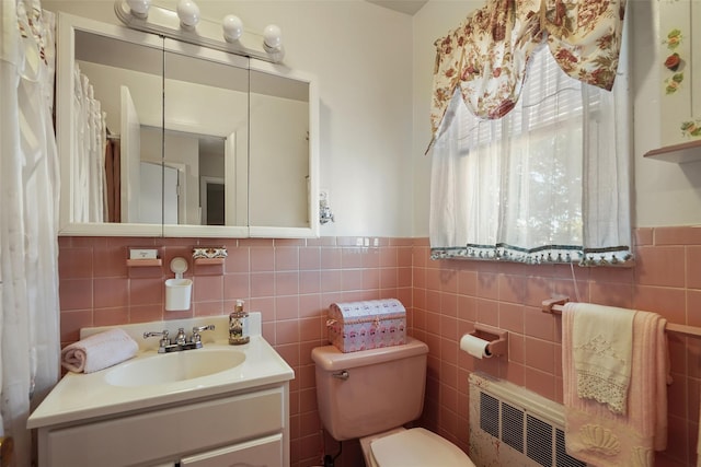 bathroom with vanity, toilet, tile walls, and radiator