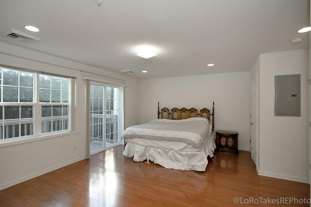 bedroom featuring electric panel, wood-type flooring, and access to exterior