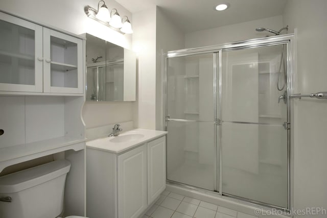 bathroom with tile patterned floors, vanity, toilet, and an enclosed shower