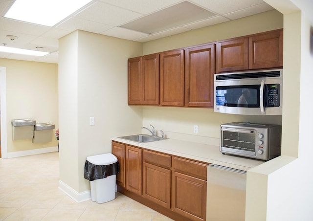 kitchen featuring a paneled ceiling, light tile patterned flooring, and sink