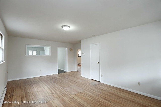 unfurnished room with a healthy amount of sunlight, baseboard heating, and light hardwood / wood-style floors