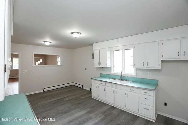 kitchen with a healthy amount of sunlight, sink, white cabinets, and baseboard heating