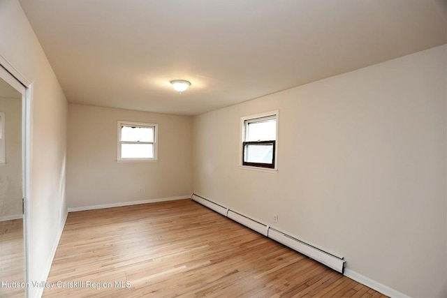 spare room with a healthy amount of sunlight, light hardwood / wood-style flooring, and a baseboard heating unit