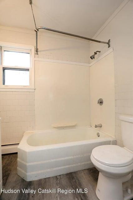 bathroom featuring hardwood / wood-style flooring, tiled shower / bath combo, ornamental molding, a baseboard radiator, and toilet