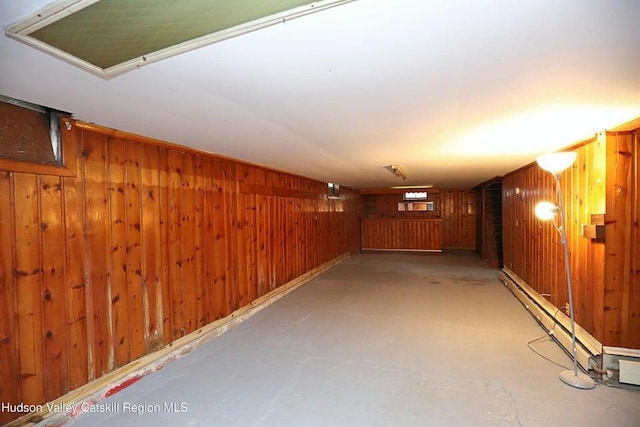 basement with a baseboard radiator and wood walls