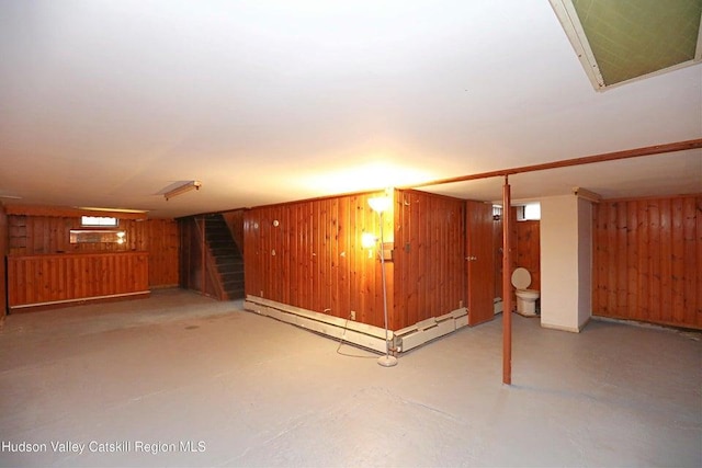 basement featuring a baseboard heating unit and wooden walls