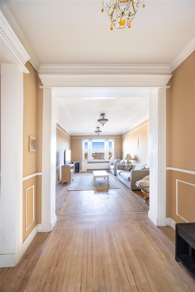 living room with a notable chandelier, light wood-type flooring, and crown molding