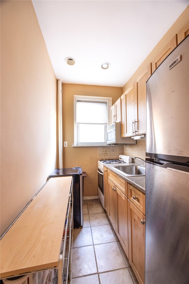 kitchen featuring backsplash, sink, light brown cabinetry, appliances with stainless steel finishes, and light tile patterned flooring