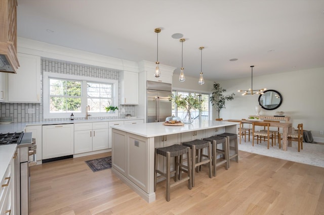 kitchen with hanging light fixtures, appliances with stainless steel finishes, white cabinetry, and a kitchen island