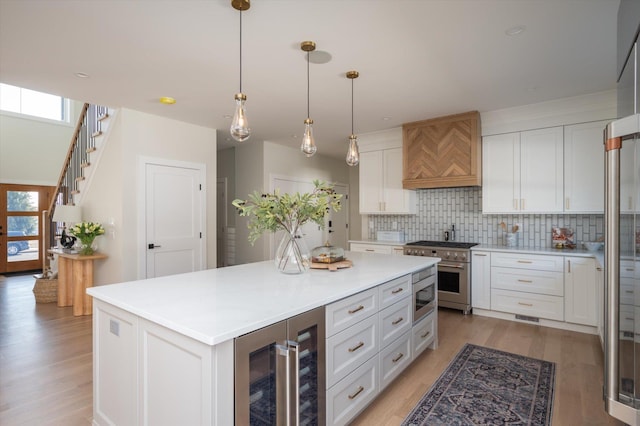 kitchen featuring custom exhaust hood, a kitchen island, white cabinetry, stainless steel appliances, and wine cooler