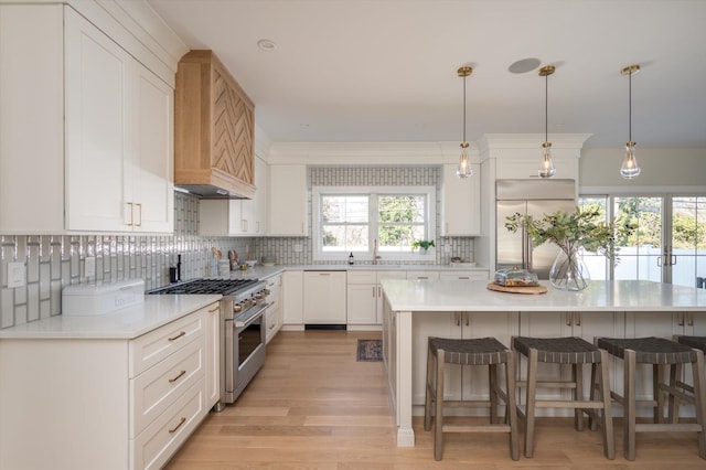 kitchen with pendant lighting, high quality appliances, white cabinetry, and a kitchen island