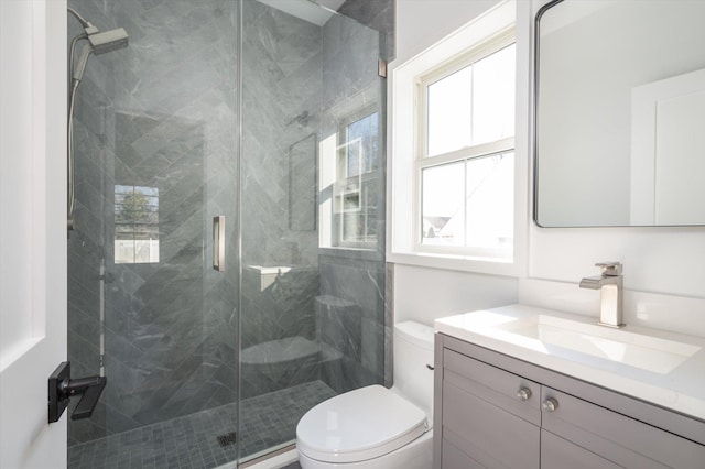 bathroom featuring toilet, a wealth of natural light, walk in shower, and vanity