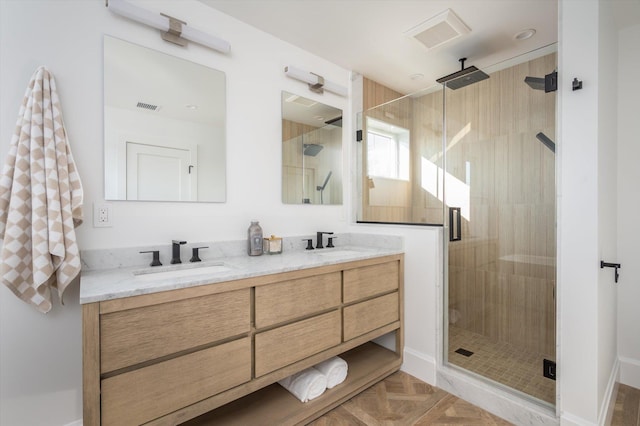 bathroom featuring an enclosed shower, vanity, and parquet flooring