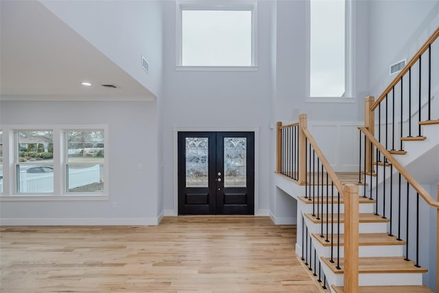 entrance foyer featuring a healthy amount of sunlight, visible vents, wood finished floors, and french doors