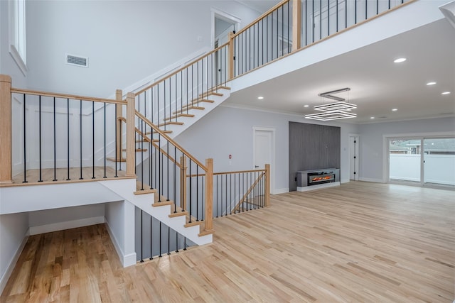 stairway featuring baseboards, visible vents, a towering ceiling, wood finished floors, and recessed lighting