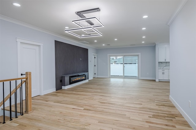 unfurnished living room featuring light wood-type flooring, a large fireplace, crown molding, and recessed lighting