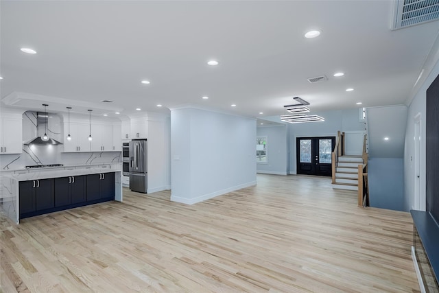 kitchen featuring open floor plan, wall chimney exhaust hood, visible vents, and stainless steel fridge with ice dispenser