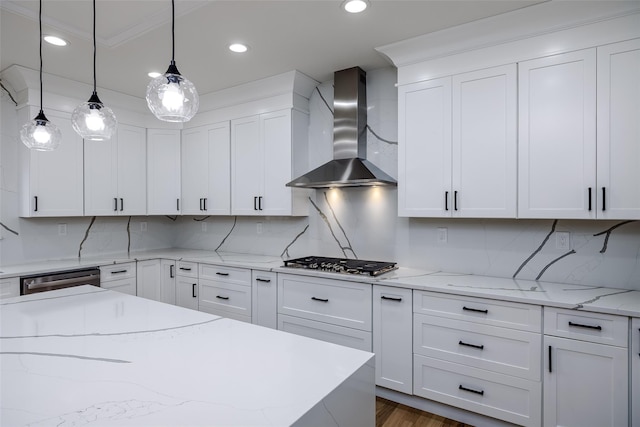 kitchen featuring stainless steel appliances, pendant lighting, white cabinetry, and wall chimney range hood