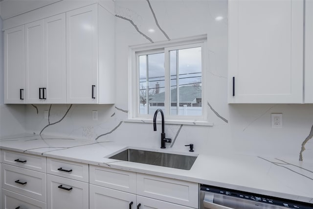 kitchen featuring tasteful backsplash, stainless steel dishwasher, a sink, and white cabinets