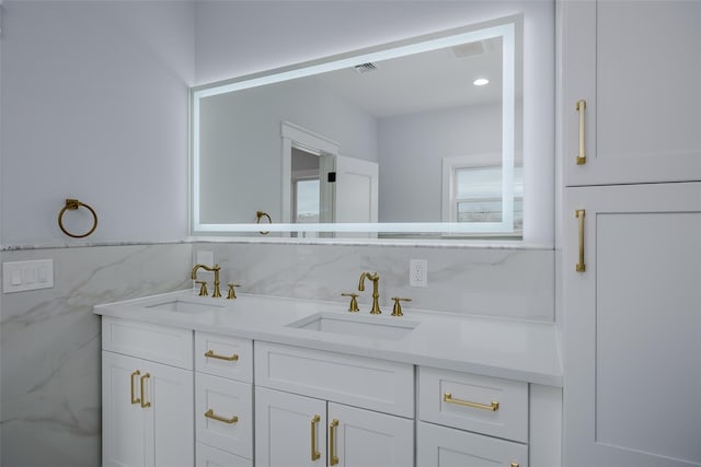 bathroom with double vanity, a sink, visible vents, and tile walls