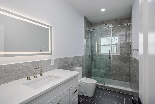 full bathroom featuring toilet, tile patterned flooring, vanity, a shower stall, and tile walls