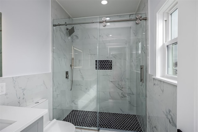 full bathroom featuring toilet, a marble finish shower, tile walls, and vanity