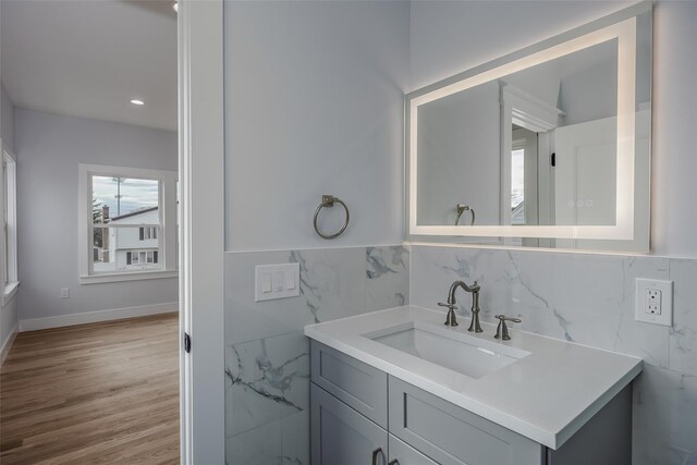 bathroom with wood finished floors, vanity, and tile walls