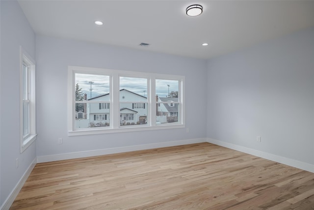 unfurnished room featuring light wood finished floors, recessed lighting, visible vents, and baseboards