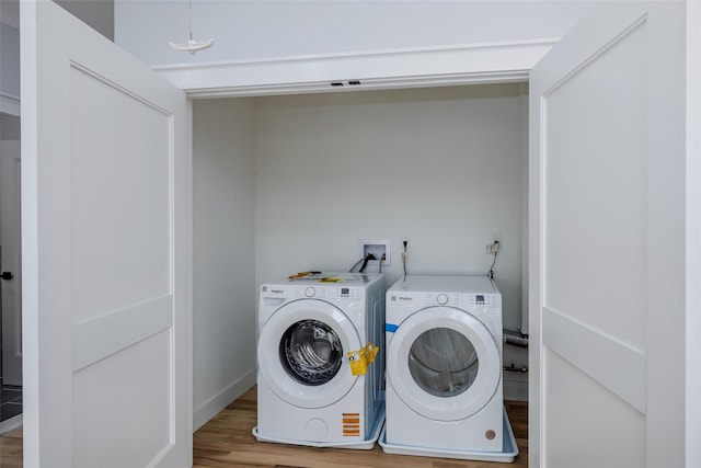 laundry area with laundry area, washer and clothes dryer, and wood finished floors