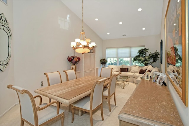 dining area featuring high vaulted ceiling, an inviting chandelier, and light colored carpet