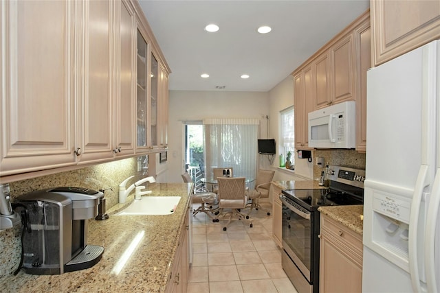 kitchen featuring white appliances, light tile patterned floors, light brown cabinetry, light stone counters, and sink