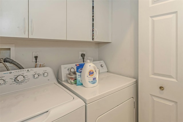 clothes washing area with washer and dryer and cabinets