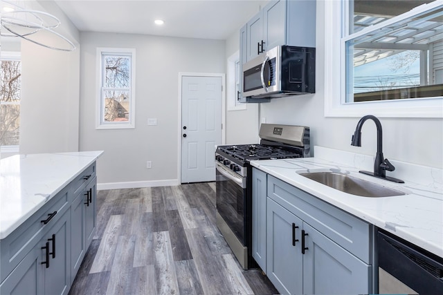 kitchen featuring light stone countertops, appliances with stainless steel finishes, dark hardwood / wood-style flooring, and sink