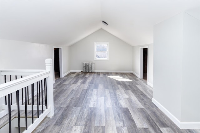 bonus room with radiator heating unit, wood-type flooring, and vaulted ceiling