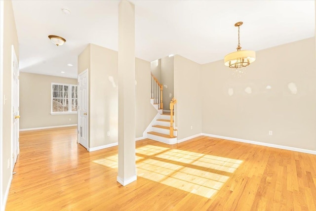 spare room featuring a notable chandelier and light hardwood / wood-style floors