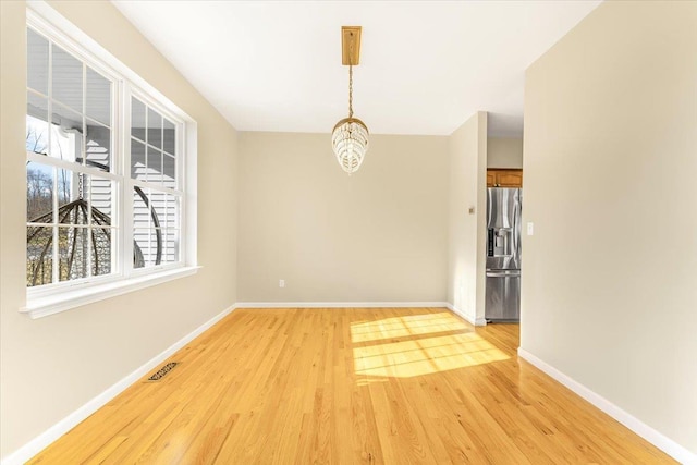 unfurnished dining area featuring light hardwood / wood-style floors and a notable chandelier