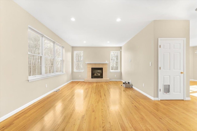 unfurnished living room featuring light hardwood / wood-style floors, a fireplace, and a wealth of natural light