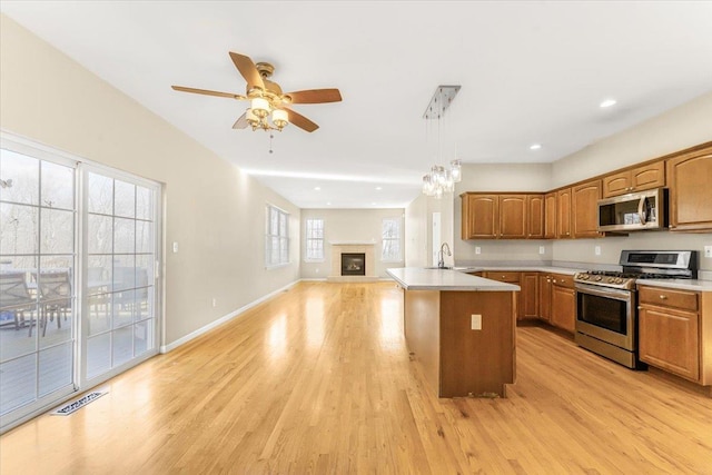 kitchen with a center island, hanging light fixtures, stainless steel appliances, light hardwood / wood-style floors, and ceiling fan with notable chandelier