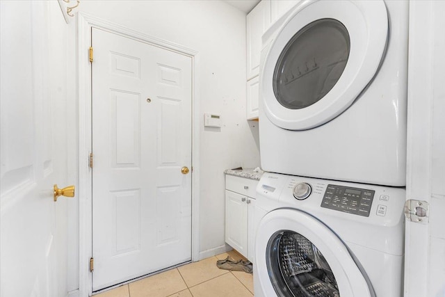 washroom with cabinets, light tile patterned floors, and stacked washer and clothes dryer