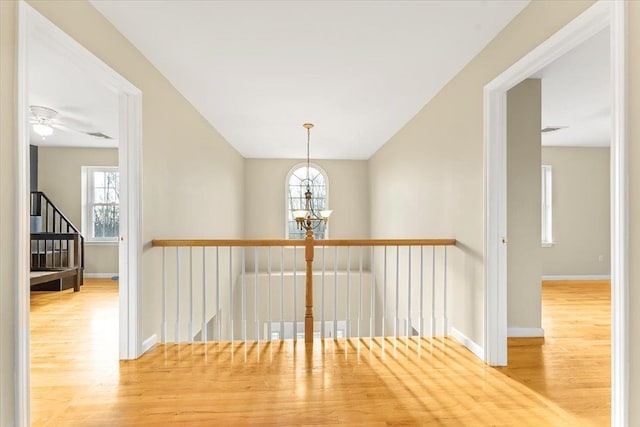 hallway featuring wood-type flooring and an inviting chandelier