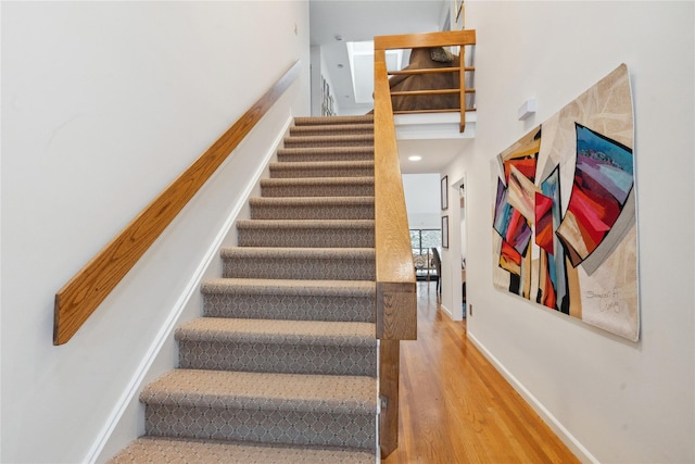 stairs with wood-type flooring and a towering ceiling