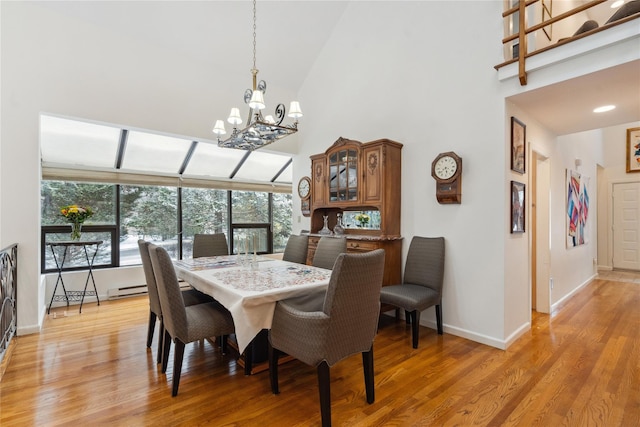 dining space with an inviting chandelier, high vaulted ceiling, a baseboard heating unit, and light hardwood / wood-style flooring